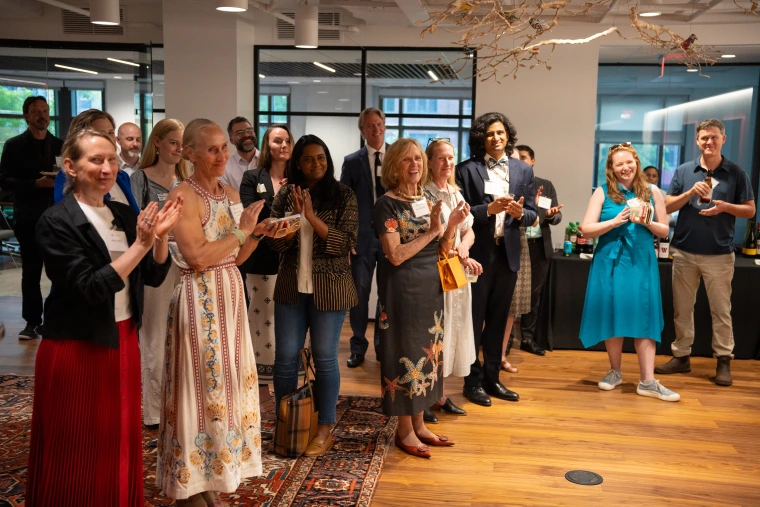 A crowd in formal dress applaud. 